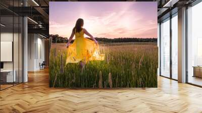 An Asian woman with long hair and yellow dress dances, rejoices, laughs under sunset with sunstar / sunburst Wall mural