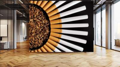 Empty cigarette tubes with yellow filter and poured tobacco in centre on black table for homemade sleeve stuffing top view      Wall mural