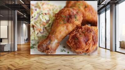 Crispy fried chicken drumsticks served with coleslaw on a plate in a rustic dining setting Wall mural