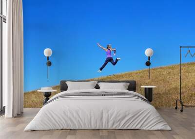 happy young woman jumping from the hill. girl running down the mountain. Wall mural