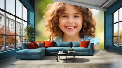 Happy beautiful cheerful child girl outdoors in spring or summer with blooming flowers in park. curly kid smiling nd looking at camera Wall mural