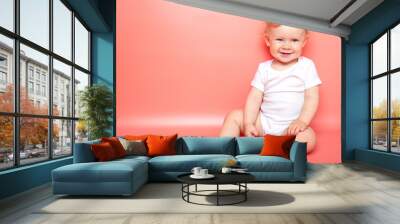 portrait caucasian curly blond smiling baby girl sitting on pink background wearing in white t-shirt. copy space. Wall mural