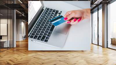 Hand holding credit card and using laptop. Businesswoman or entrepreneur working from home. Online shopping, e-commerce, internet banking, spending money, work from home concept Wall mural