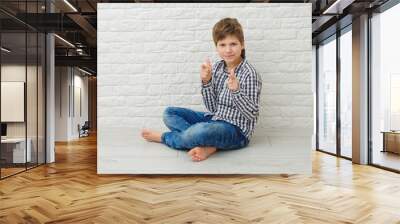 Handsome healthy young boy smiling with his finger pointing isolated on light banner background with copy space Wall mural