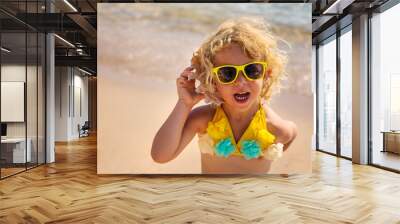 Child listening to a seashell on the sea. Selective focus. Wall mural