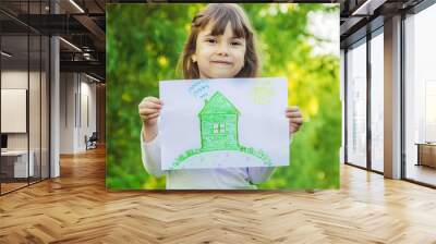 Drawing of a green house in the hands of a child. Selective focus.  Wall mural