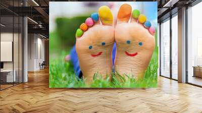 Feet of a child on the grass with a painted smile. Selection focus. Wall mural