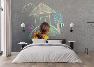 The child draws a house on the asphalt. Selective focus. Wall mural