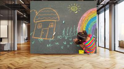 The child draws with chalk on the asphalt. Selective focus. Wall mural