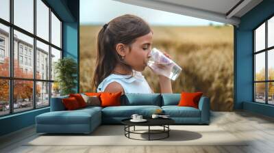 The child drinks water from a glass. Selective focus. Wall mural