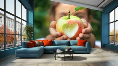 The child eats an apple in the garden. Selective focus. Wall mural