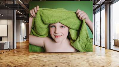 Cute funny blond boy with towel on green background. Child in towel with wet hair. Soft focus Wall mural