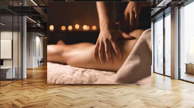 A masseur in a dark room does a hip massage with oil for a woman. Spa procedures massage women Wall mural