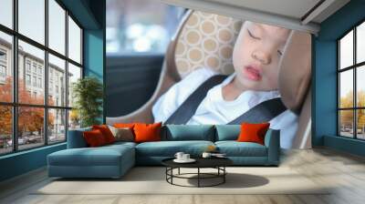 Cute little Asian 2 -3 years toddler baby boy child sleeping in modern car seat. Child traveling safety on the road. Safe way to travel fastened seat belts in vehicle with young kid concept Wall mural