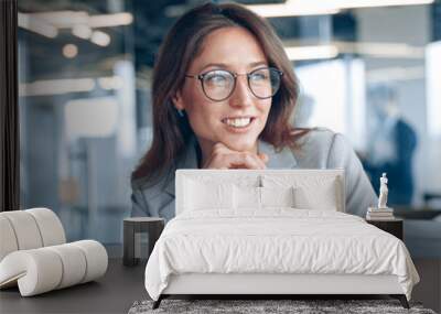 businesswoman working on laptop and looking out the window at her workplace in modern office. Wall mural