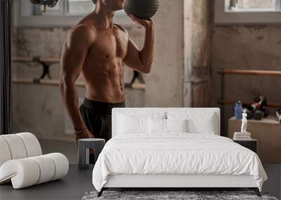 cropped of confident young man with athletic body holding exercise ball in hand while standing in sp Wall mural