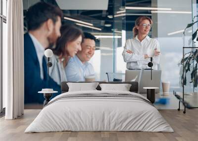 Smiling confident female boss looking at side on business meeting with colleagues in office Wall mural