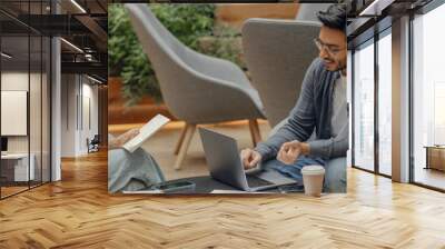 Two business colleagues working together on project while using laptop in modern coworking Wall mural