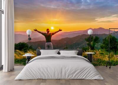 rejoicing man with beautiful scenic mountain sunset landscape on background. happy man watching amazing evening sunset Wall mural