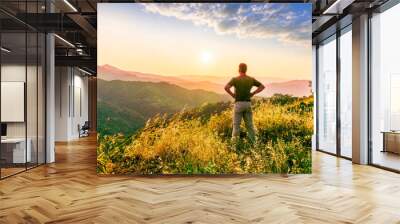 rejoicing man with beautiful scenic mountain sunset landscape on background. happy man watching amazing evening sunset Wall mural