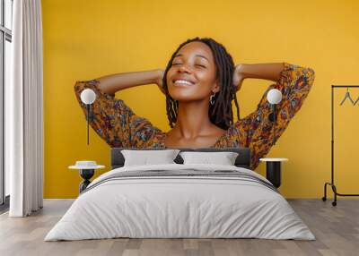 A happy woman with braided hair, wearing a flowy blouse, with her hands in the air, posing against a plain yellow background , natural, cheerful, fashion Wall mural