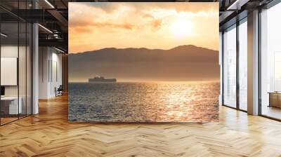 tropical seascape of sailing kargo tanker ship in sea with beautiful sunset and mountains on background Wall mural