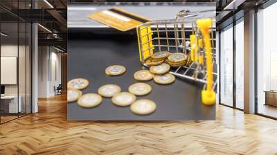 Shopping cart with scattered gold coins and a credit card near the laptop close-up. The concept of shopping online, shopping on credit Wall mural