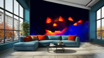 Two glowing pumpkins in the dark in the smoke in the forest close-up. One pumpkin peeks out from behind another. Beautiful background for Halloween. Wall mural