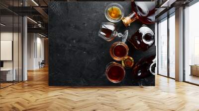 A bottle of cognac and glasses on a black background. Brandy. Top view. Free space for your text. Wall mural