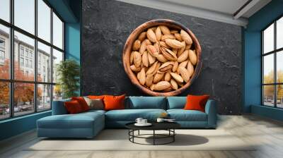 Almond nut in a bowl. Nuts on a black stone background. Top view. Free space for your text. Wall mural