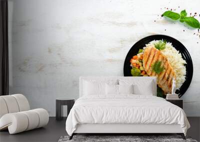 Baked chicken fillet with rice and vegetables on a black plate. Top view. Free copy space. Wall mural