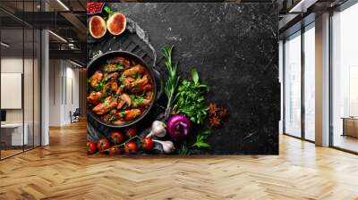 Baked mushrooms with chicken fillet in tomato sauce. In a black stone plate. Top view. Wall mural