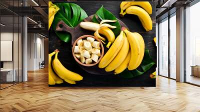 Bananas on a black wooden surface. Tropical Fruits. Top view. Free copy space. Wall mural