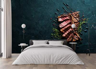 Beef T-Bone steak on a black table. Top view. Free space for text. Wall mural