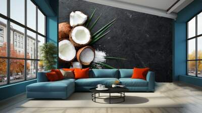 Coconut with palm leaves on a black stone background. Tropical Fruits. Nut. Top view. Free space for your text. Wall mural