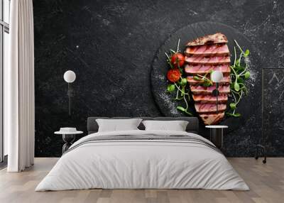 Cooked juicy tuna steak with vegetables on a black stone plate. Restaurant food. Seafood. Rustic style. Flat Lay. Wall mural