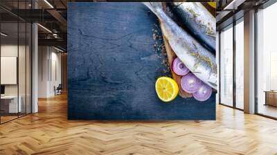 Fresh fish with vegetables, spices and oil. On a black wooden background. Free space for text . Top view Wall mural