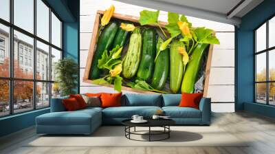 Green zucchini in a wooden box. Fresh vegetables. On a white wooden background. Top view. Copy space. Wall mural