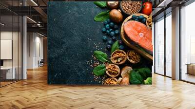 Heart health foods: salmon, avocados, blueberries, broccoli, nuts and mushrooms. On a black stone background. Top view. Copy space. Wall mural