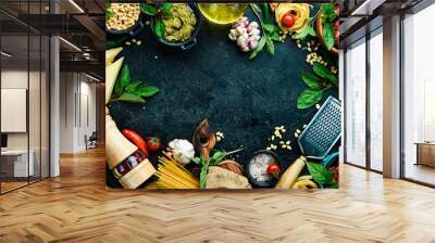 Kitchen banner with ingredients for cooking: pasta, cheese, greens, vegetables and spices. On a black stone background background. Wall mural