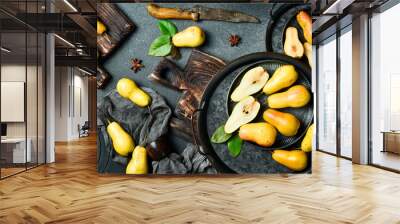 Pears on plates. There are slices of pears and a knife on the cutting board. Top view. On a black stone background. Wall mural