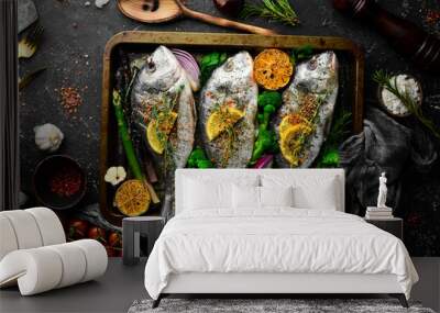 Raw Dorado fish with vegetables in a metal tray. Fish cooking recipe. Top view. Free copy space. On a black stone background. Wall mural