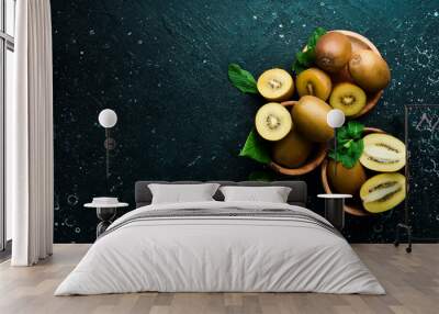 Ripe gold kiwi fruits on a wooden board. On a black stone background. Top view. Wall mural