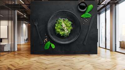 Seaweed salad in a black plate. Chuka wakame On the old background. Top view. Free space for your text. Wall mural