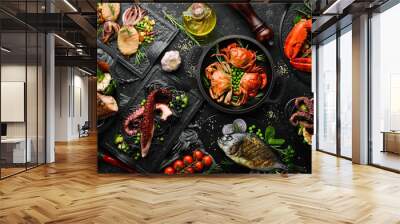 Set of seafood dishes. Fish, squid, octopus on a black stone background. Top view. Free space for your text. Wall mural