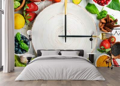 The concept of dietary nutrition: fresh vegetables and fruits. Cutlery and a plate in the form of a clock. Top view. Free space for your text. Wall mural