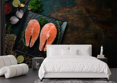 Two raw salmon steak with rosemary on a black stone plate. On a dark background. Top view. Wall mural