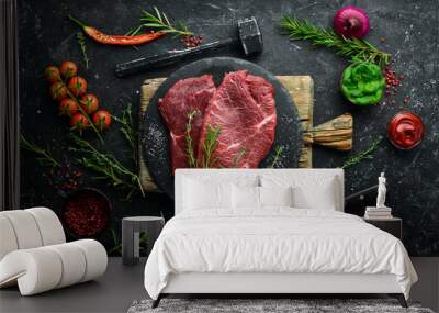 Two raw veal steaks with rosemary and spices. On black stone background. Top view. Wall mural