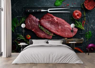 Two raw veal steaks with rosemary and spices. On black stone background. Top view. Wall mural