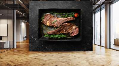 Two veal steaks on the bone with spices, thyme and rosemary. Barbecue meat. Top view. Flat lay top view on black stone cutting table. Wall mural